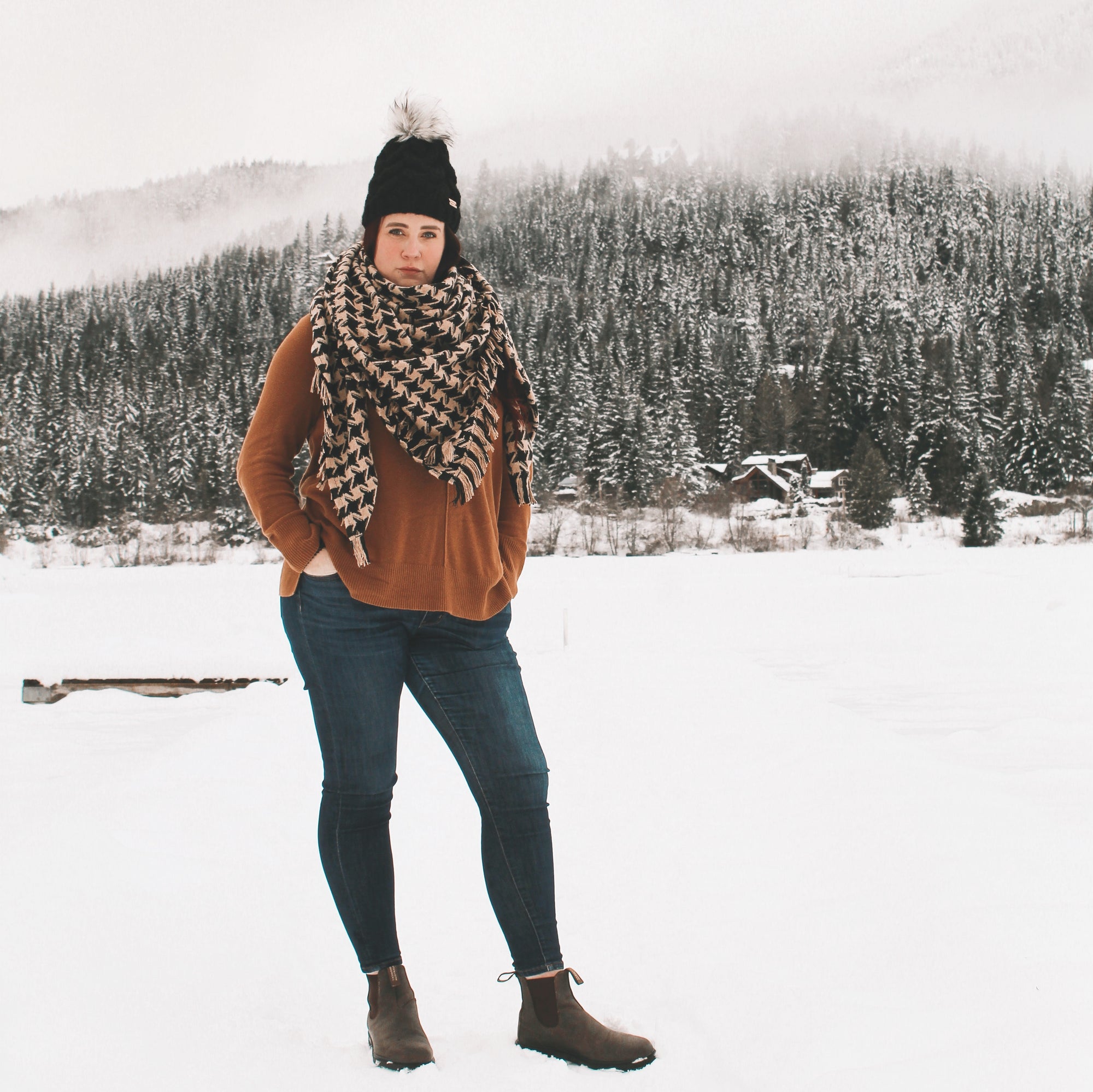 Woman modelling a blanket scarf made by West Coast Alchemist in Whistler BC, snow and trees in the back ground 